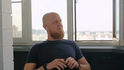 A bald man with a red beard listens to music from a smartphone and moves to beat Stock Footage 142581335