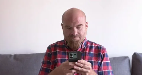 Bald Man with Red Goatee Using Smartphone to Scroll on Social Media Stock-Footage 295143819