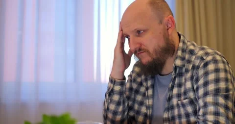 Bald man rubs forehead while stress builds in hectic workspace letting stress Stock Footage 301525407