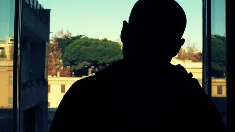 Bald man in shadow appears at the window Stock Footage 71017354