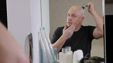 A bald man with shaving foam on his head in the bathroom, he shaves his head. Stock Footage 305293330