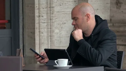 Bald man smiling  send a sms sitting at the bar Video stock 74718308