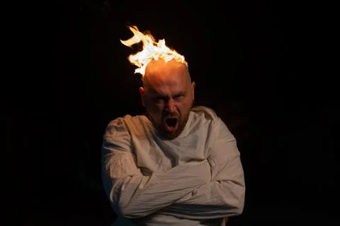 Bald man in a straitjacket with a burning head on a dark background. Stock Photos