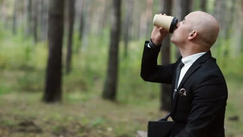 Bald man in a suit drinks coffee from a cup Stock Footage 147329174