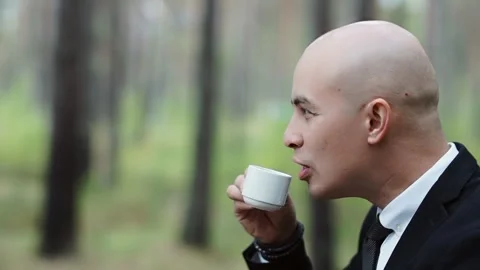 Bald man in a suit drinks coffee from a small cup Stock Footage 147329349