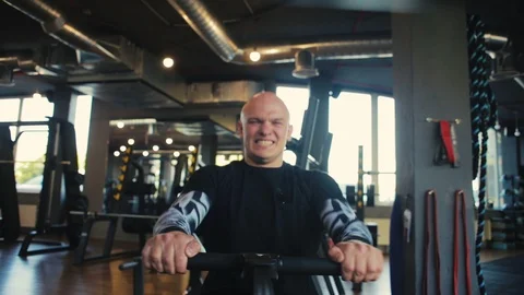 Bald man trains on rowing machine and has cardio workout Video stock 110575334