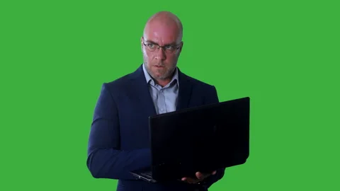A bald man typing and programming a laptop and looking intently at the Stock Footage 285058971