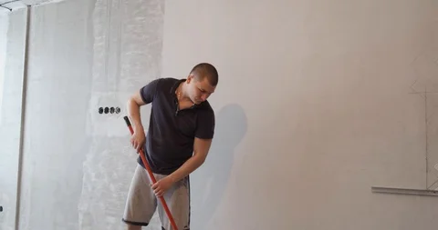 Bald man using roller puts primer on white wall. Prepares wall for wallpapering Stock Footage 128972540