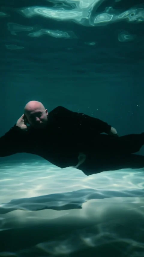 A bald millennial man super agent poses for a photo underwater Stock Footage 315558302