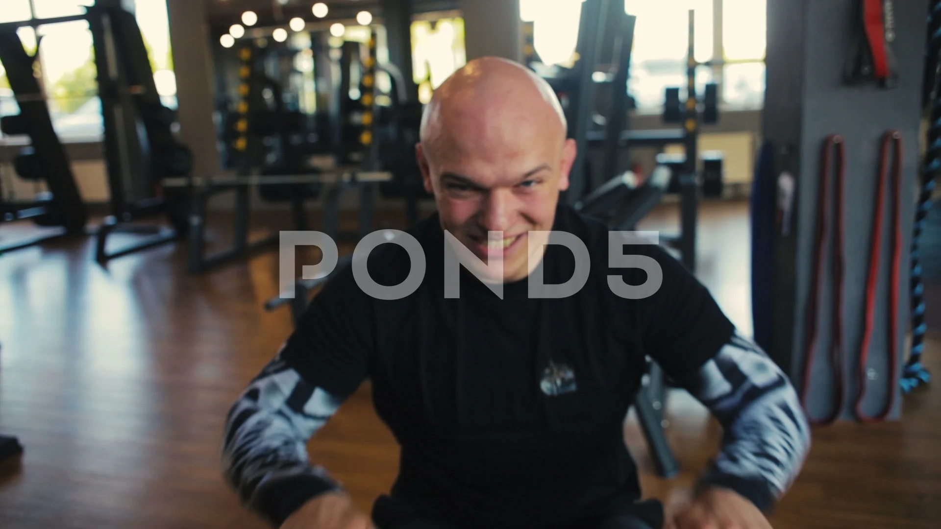 bald muscular guy in black dressing breathes deeply in gym