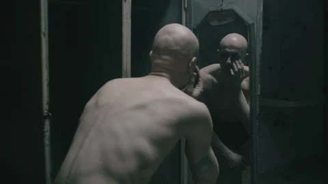 Bald person in the prison looking at himself in the mirror Video stock 259683451