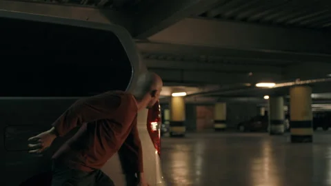 Bald thief hiding behind a grey car Stock Footage 283065238