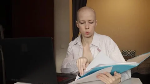 Bald woman using computer and reviewing papers at home office, concept of t.. Stock Footage 319946014