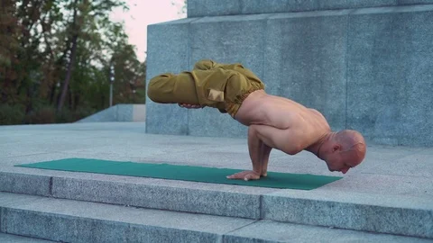 Bald Young Man Balances Standing on Hands Practicing Yoga Exercises in the City Stock Footage 85331084