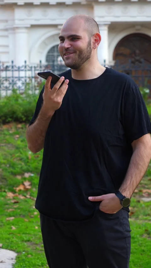 Bald Young Man Smiling While Talking on Smartphone in City Park 库存影片 328644477