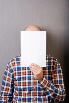 Balding man holding a blank paper in front of face Stock Photos