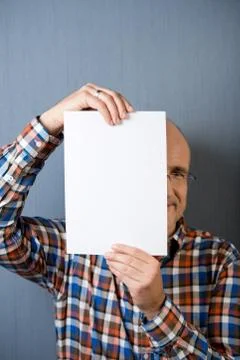 Balding man holding a blank paper in front of face Stock Photos