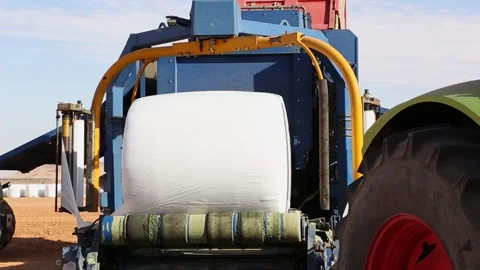 Bale wrapper wrapping a bale of hay with plastic film in a field 스톡 동영상 318831341