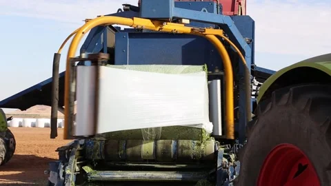 Bale wrapper wrapping a bale of hay with plastic film in a field 스톡 동영상 318831355