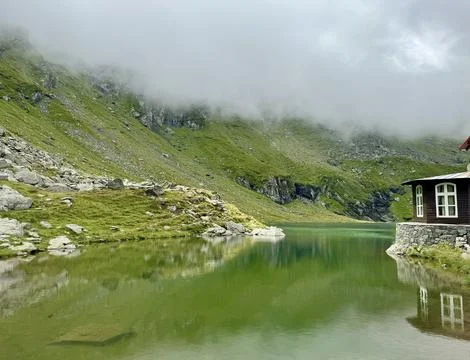 Bâlea Lake Chalet reflected in calm alpine lake, Romania Stock Photos