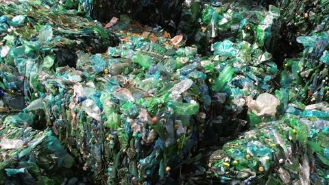 Bales of crushed green plastic bottles at recycling plant facility showing .. Stock Footage 339647177