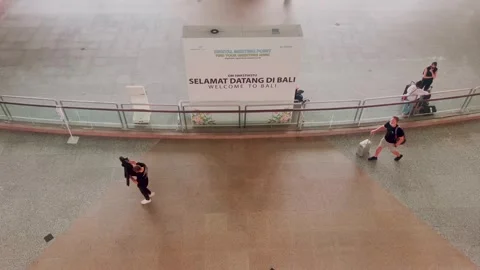 Bali, 5 Jan 2023: Inside Balis modern airport terminal, travelers move with.. Stock Footage 310639085