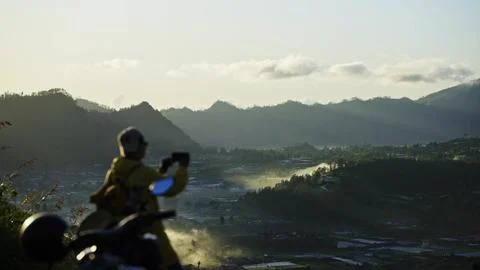 Bali, silhouette of a man standing on top of a mountain and photographing Stock Photos