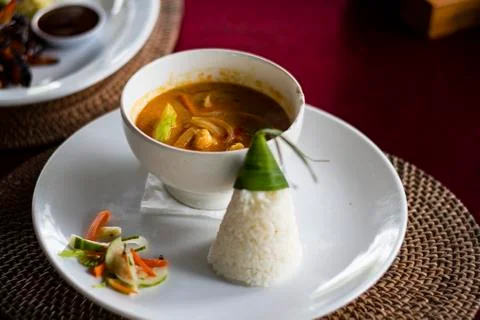 Balinese chicken gravy dish served with traditional cone shaped leave wrapped Stock Photos