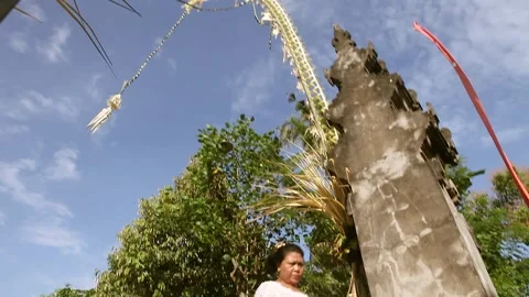 Balinese enter and exit the temple against a backdrop of trappings and blue sky Stock Footage 302588101