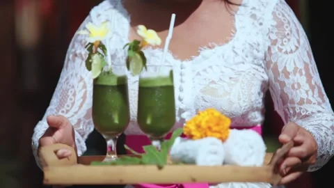 Balinese Waitress Serving Welcome Drinks and Cold Towels on a Wooden Tray Stockbeeldmateriaal 339410079