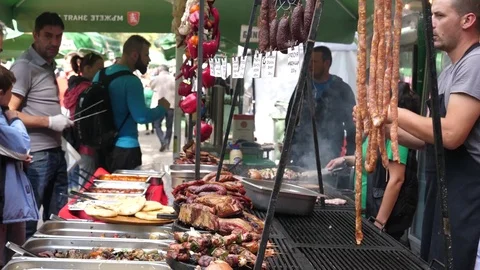 Balkan meat dishes layout and people buy diverse food at street festival Video stock 80635449