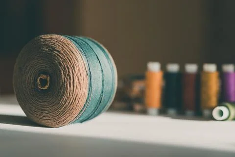 Ball of beige thread on table with colorful tangles in the background. Brave Stock Photos