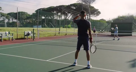 Ball bouncing causing Asian male player tracking tennis rally joining partner Stock Footage 340972266