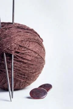 A ball of brown thread and two knitting needles in it. Nearby are two brown butt Stock Photos