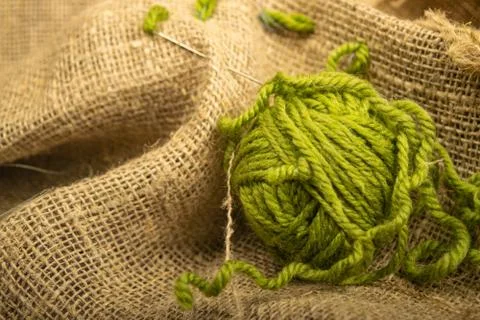 A ball of green thread on rough-textured burlap. Close up. Stock Photos