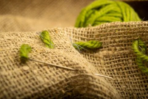 A ball of green thread on rough-textured burlap. Close up. Stock Photos