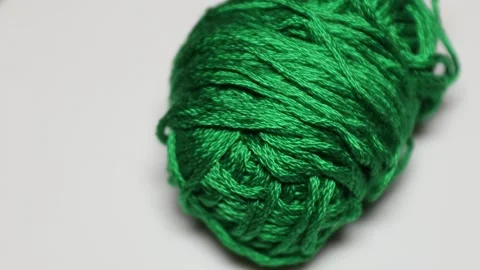 A ball of green yarn sits on a white surface, ready for crafting or knitting Видео 337048158