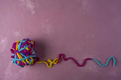 A ball of multi-colored threads for knitting on a pink background Stock Photos