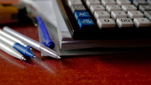 Ball pens , calculator on white papers pan shot Stock-Footage 106932794