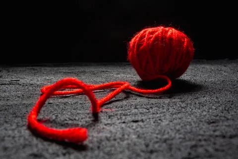 Ball of red thread for knitting on black concrete dark background .copy space Stock Photos
