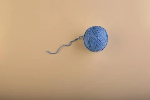 A ball of thread for knitting, soft blue, is slightly unwound on a harmonious Stock Photos