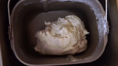 A ball of white dough rests in a bread maker pan, ready to rise and bake in a Stock-Footage 325096423