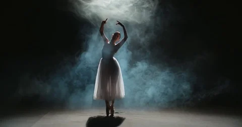 Ballerina dancing elements of classical ballet in the dark with light and smoke Видео 83858396