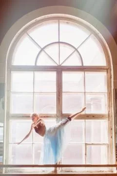 Ballerina is dancing in front of a large window Stock Photos