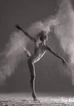 Ballerina performs arabesque pose against background of white flour cloud in  Stock Photos