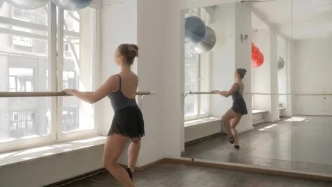 Ballerina performs squats on one leg standing at the barre in front of a mirror. Stock Footage 287238843