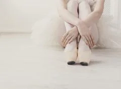 Slim legs of young ballet dancer in white tights and beige silk pointe  shoes Stock Photo by Pressmaster