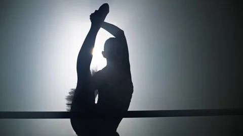 Ballerina stretches near the ballet barre in the dance hall. Vídeos de archivo 241399394