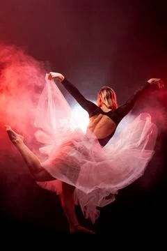 Ballerina with a white dress and black top posing on red smoke background Stock Photos