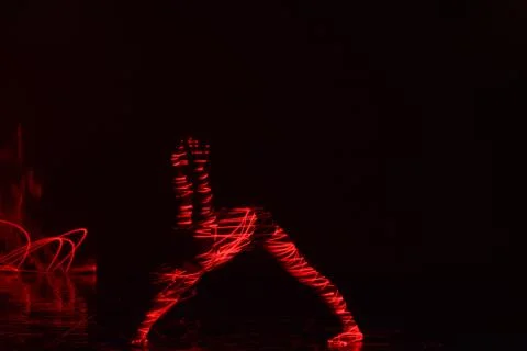 Ballet dancer dancing in front of and red light while expressing the hell wit Stock Photos
